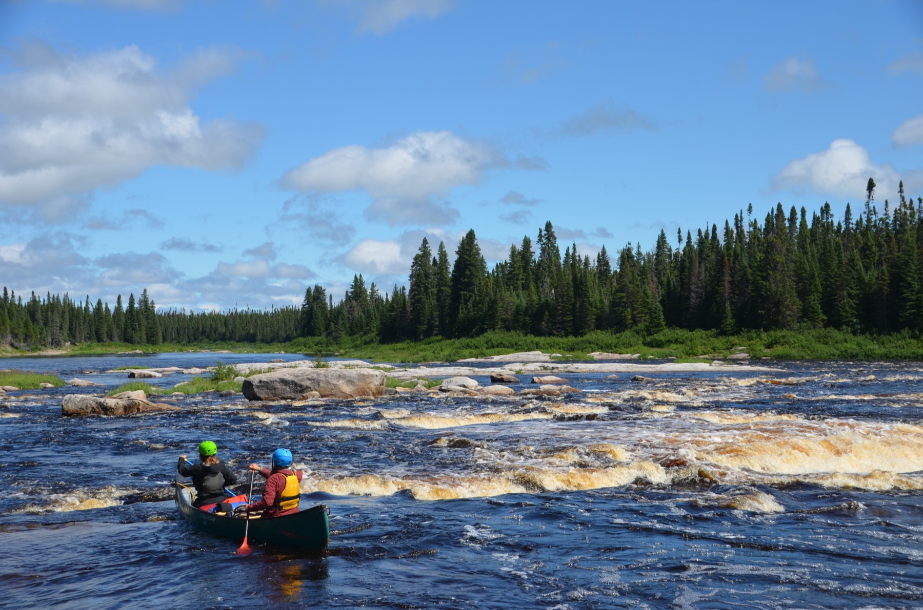Two campers paddling a canoe through wilderness rapids