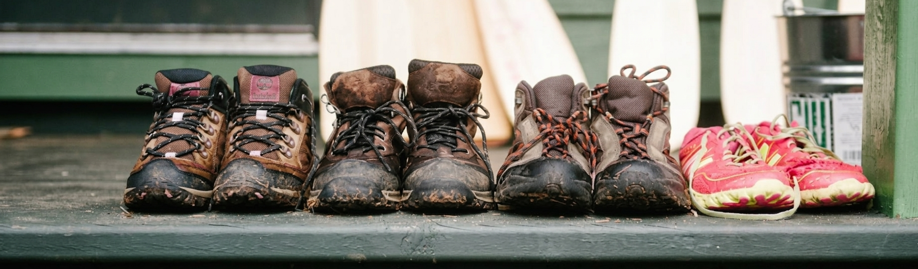 A row of muddy camp boots lined up on a cabin step